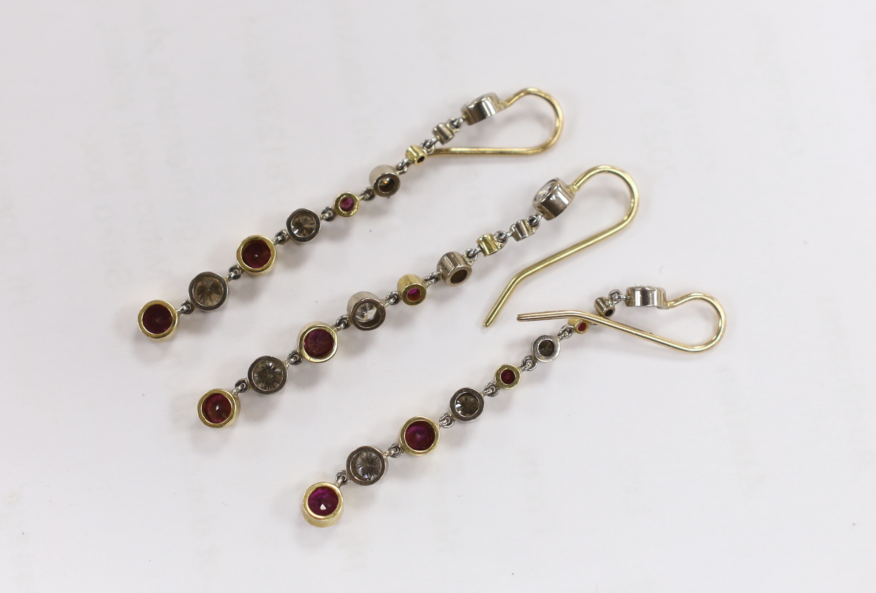 Three yellow metal and graduated ruby and diamond cluster set line drop earrings, overall 50mm, gross weight 5.7 grams.